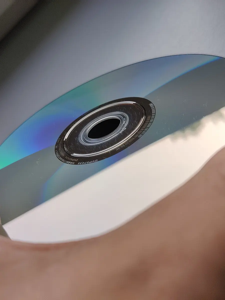 A hand holding a DVD-ROM by its edge