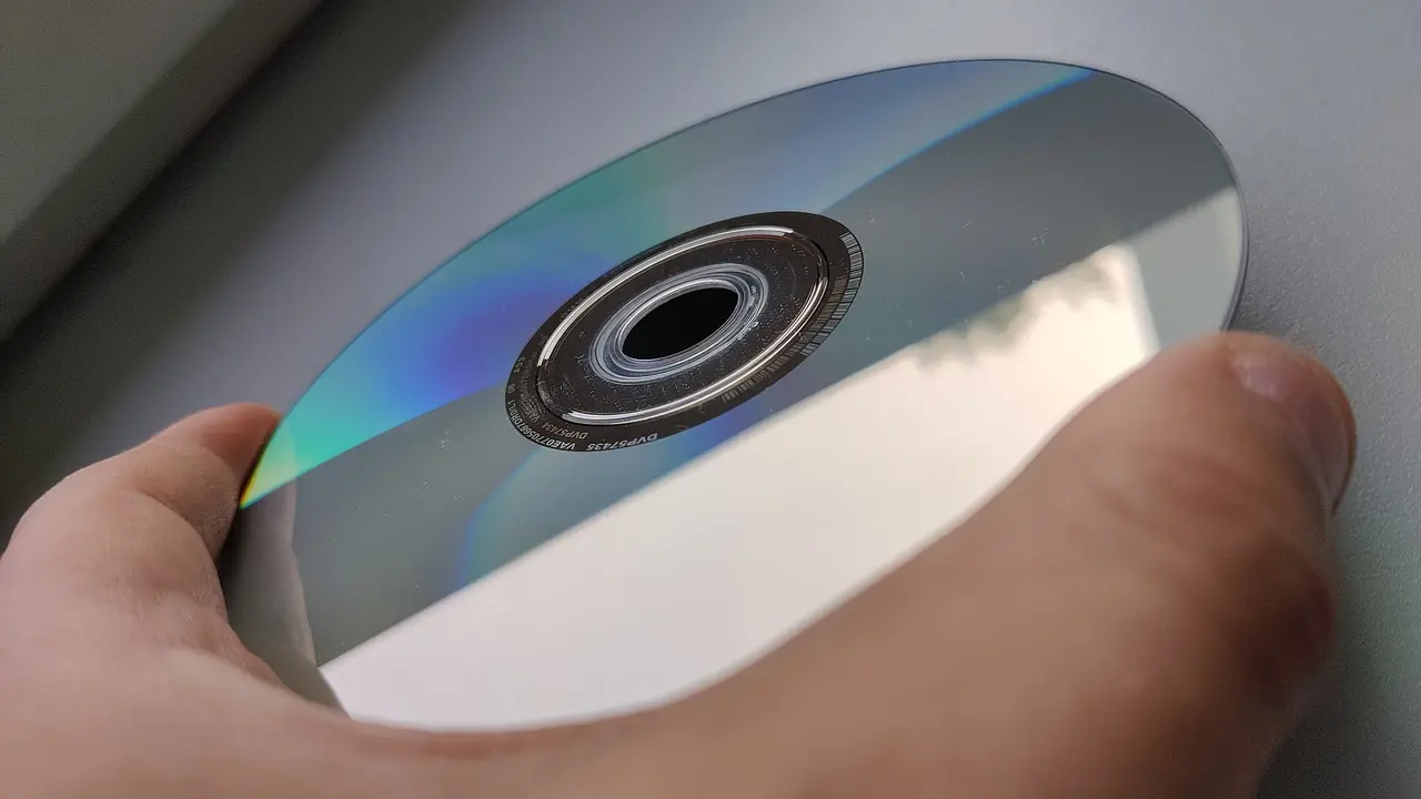 A hand holding a DVD-ROM by its edge