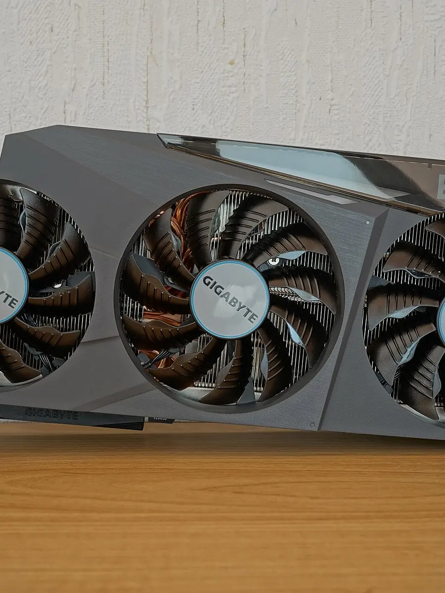A large triple-fan graphics card standing upright on a desk