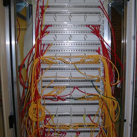 A patch panel carrying red and white network cables