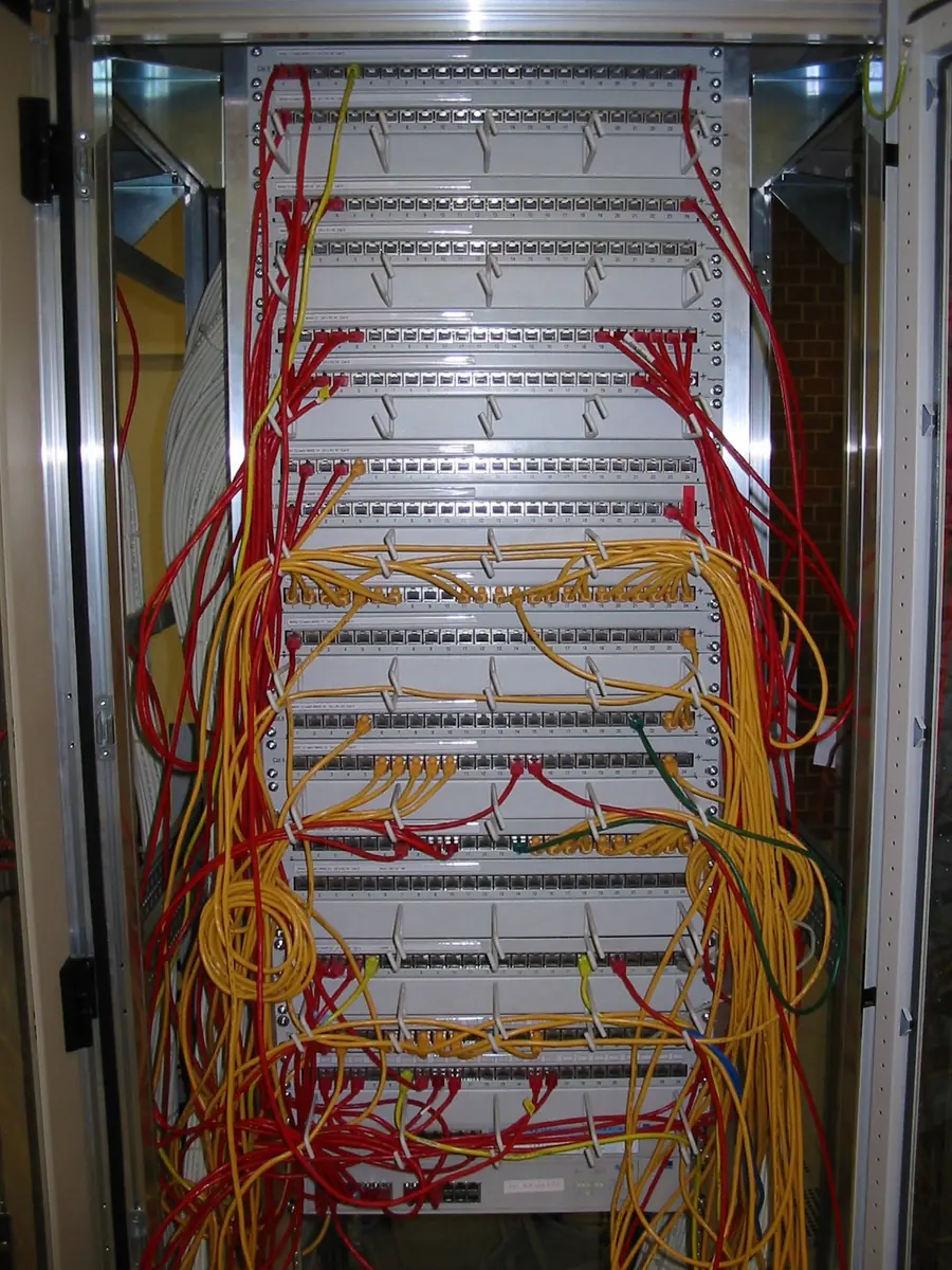 A patch panel carrying red and white network cables
