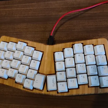 A split mechanical keyboard on a wooden desk