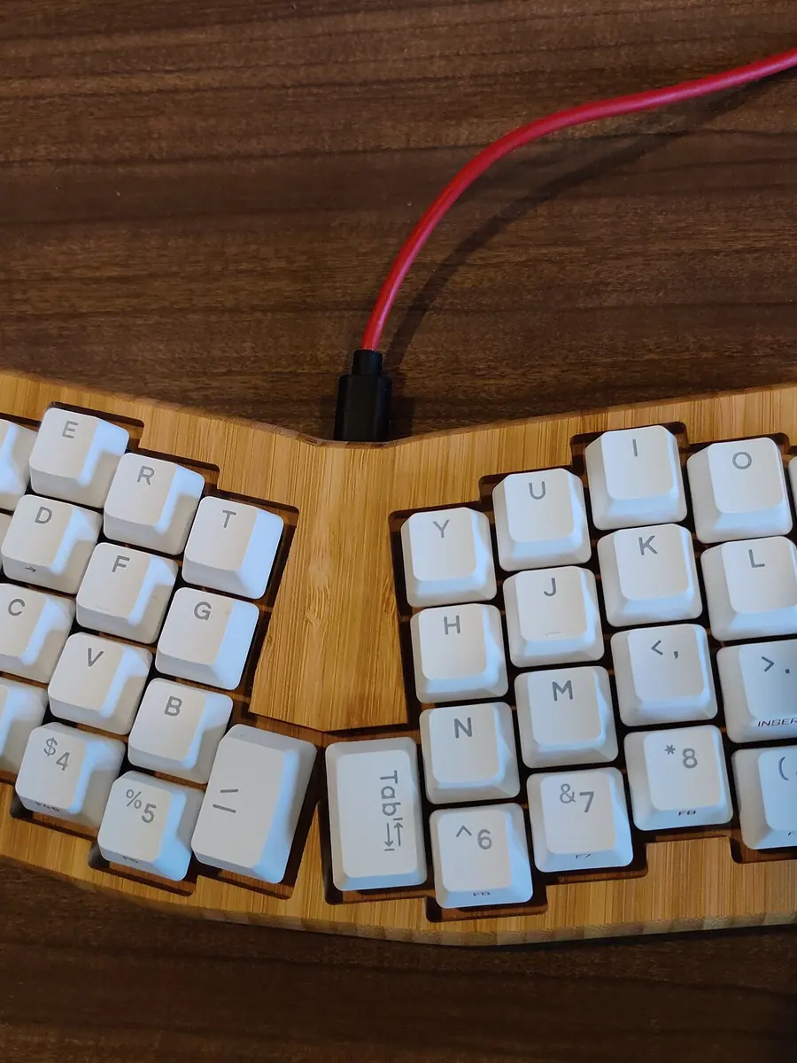 A split mechanical keyboard on a wooden desk